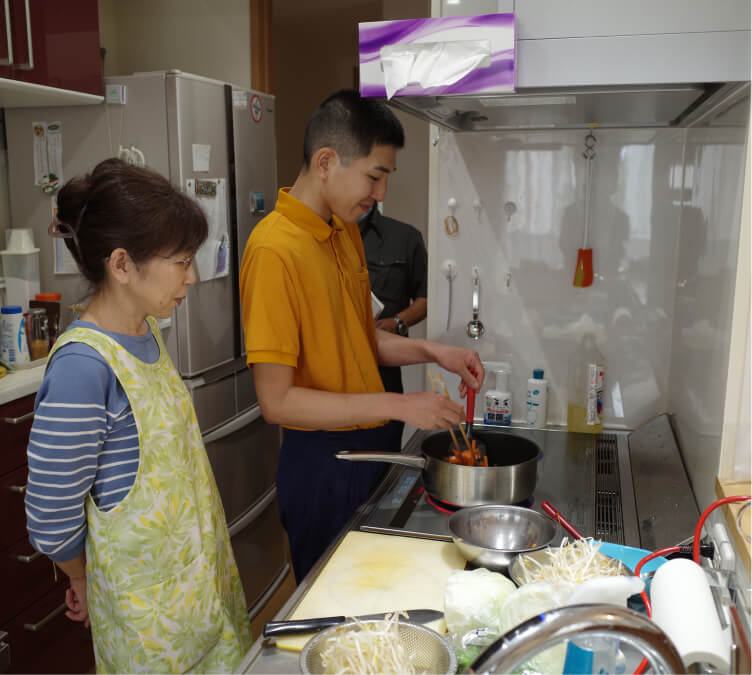 お母さんと息子が台所で調理をしています