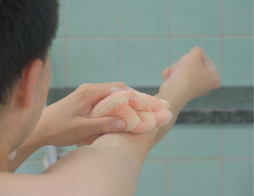 右腕に垢すりを当てて洗っています