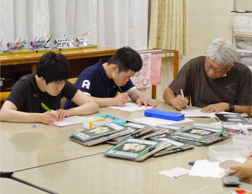 先生の近くで数人の園生が日記を書いています
