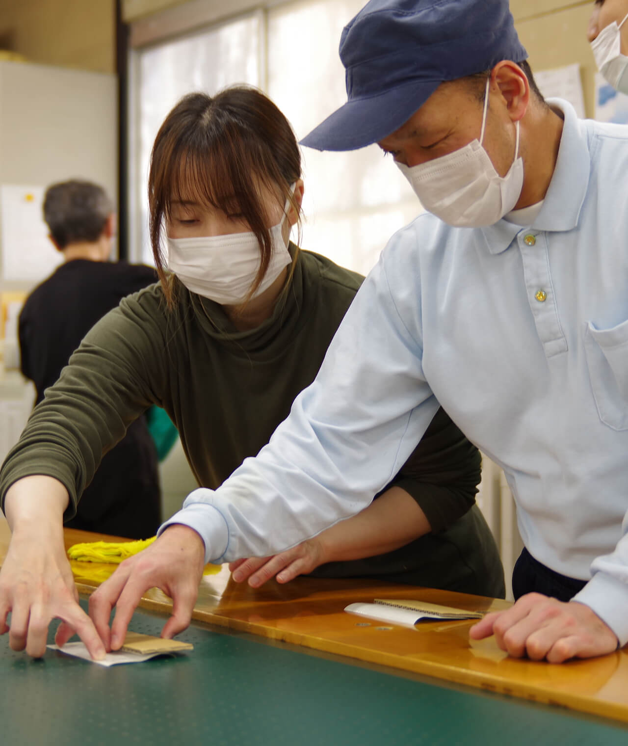 れいさんがボール紙を指先で抑えて作り方の指導をしています